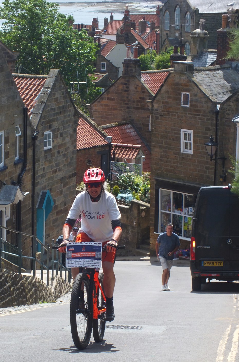 Rob cycling up a steep, narrow street in Robin Hood's Bay.
